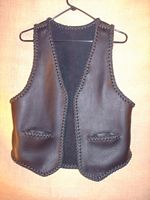  This black braided moccasin leather vest has slit hip pockets and a 3" draft flap at the back/bottom of it. 