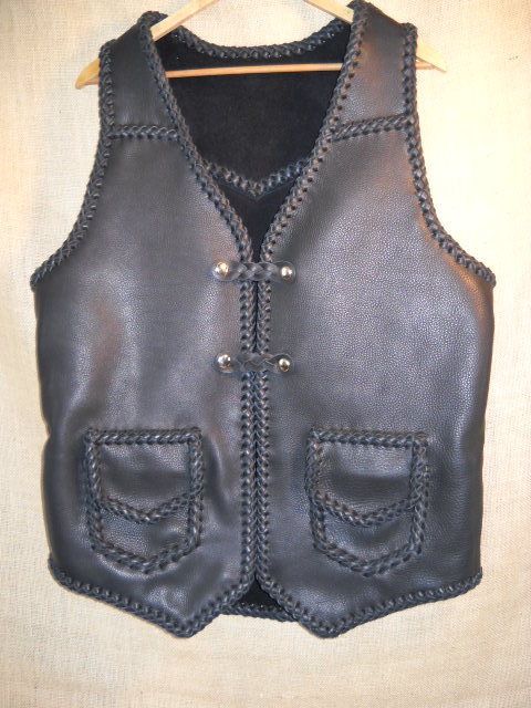  This braided motorcycle vest has slanted front yokes, a pointed back yoke, patch hip pockets with flaps, two sets of 'trick braid' leather snap closures, and a curved 3" back/bottom draft flap. This vest also has four more pockets that you can't see in this picture. 