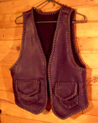  This black motorcycle leather vest was custom made in the USA with moccasin cowhide. It has two patch hip pockets with flaps and two more similar pockets on the inside using the same braiding to attach them. The inside pockets do not have flaps. 
