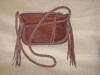  The clutch, very similar to the one at the left, has a long zippered shoulder strap with quite long tassels hanging from it. 
