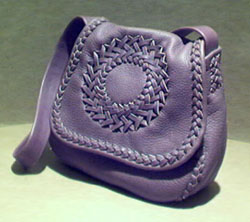  A bag using what is called the 'S' applique braid. It has a circle applique on the flap, a full width inside back pocket, and a flat wide/strong shoulder strap. 