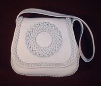  This is the front view of this Pearl colored, braided leather purse on a dark colored background. 