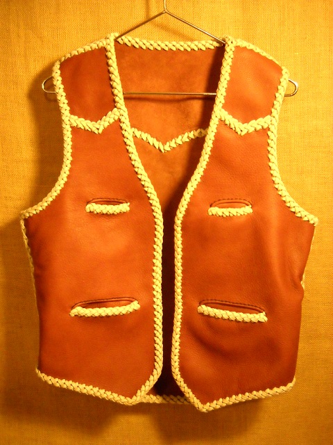  This moccasin cowhide leather vest was made in the USA. It features both front and back yokes that are all pointed. It has two slit breast pockets (credit card size) and two slit hip pockets. It also has the curved 3" draft flap extension at the back/bottom. 
