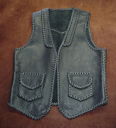  This leather vest has all of it's seams and edges braided. It also has braided lapels on the front, a pointed yoke on the back, and two patch hip pockets with flaps with matching hip pockets on the inside (without flaps). By clicking on the link, you will see more/closer pictures of it. 