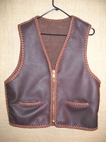  This two tone Brown leather vest is completely hand braided using moccasin cowhide leather that is tanned in the USA. It features a large brass (YKK #10) zipper and two slit hip pockets. At the buyers request, the bottom is level all the way around it. 