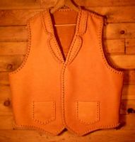 This custom and handmade leather vest was made in the USA with moccasin cowhide that was tanned in the USA. All of it's features were decided by the buyer. Those features are front split yokes, a back pointed yoke, two patch hip pockets, and conchoes that I fashioned to hang straps from. 