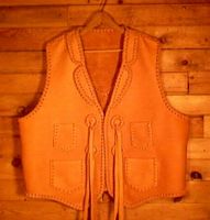  This custom and handmade leather vest was made in the USA with moccasin cowhide that was tanned in the USA. All of it's features were selected by the buyer. Those features are the front split yokes, a back pointed yoke, two patch hip pockets, and conchos that I fashioned to hang the straps from. 