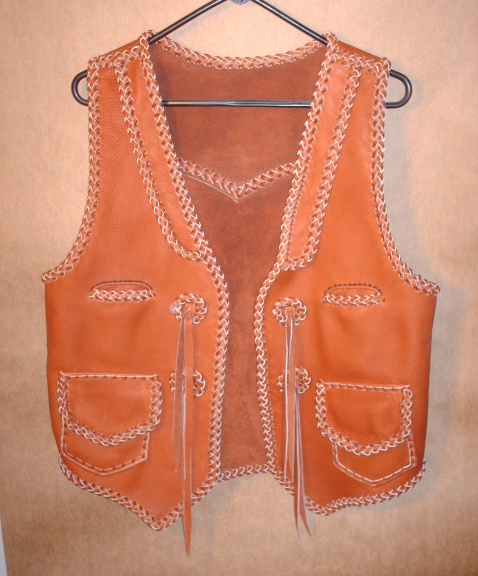 This Western style leather vest has front lapls, a back pointed yoke, two slit breast pockets, two patch hip pockets with flaps (with matching inside pockets without flaps), a back/bottom draft flap, and concoes that I fashioned for straps to hang from. 