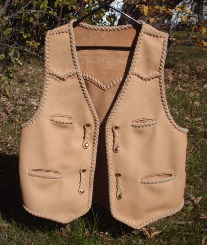  This custom leather vest was hand made in the USA for the buyer. Made of moccasin cowhide, it featurs frony pointed yokes, a back pointed yoke, two slit breast pockets (credit card size), two slit hip pockts, and with four sets of 'trick braid' straps for snap closures. It also has (what I call) a back/bottom draft flap. 
