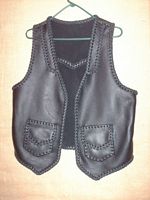  This custom black leather vest was made with moccasin cowhide leather. It's features include lapels on the front, a back pointed yoke, and two patch hip pockets with flaps. On the page that this picture is linked to is a picture of the back of it. 