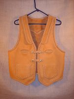 This moccasin cowhide leather vest was hand made in the USA using leather that was tanned in the USA. It features lapels, a pointed back yoke, two front slit breast pockets (credit card size), two patch hip pockets (without flaps), and two set of 'trick braid' snap closures. Clicking it's link brings you to a page with some close up of these features.  