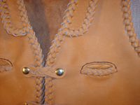  A close up of a portion of the front with its lapels, slit breast pockets, and 'trick braid' closures. 