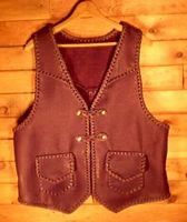  This leather vest is completely hand braided - all seams and edges. It has slanted front yokes, a pointed back yoke, patch hip pockets with flaps that include mated inside pockets (without flaps). It also has two set of 'trick braided' snaps for a closure. 
