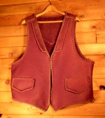 This moccasin cowhide leather vest is completely hand braided. Made in the USA, it has lapels on the front, a pointed yoke on the back, and two slit hip pockets with flaps. 