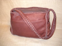  This large cowhide leather bag is similar to the other bags in this section, but, it has an open top - no flap. It has pockets on all four sides and a strap that is braided down the length of it. 