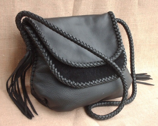 This large black leather shoulder bag is completely built with various leather braids using 1/4" wide laces. The double flaps have an edge braid, and the seams are done with an applique braid, the strap is an 8 strand round braid that has 8 long tassels that hang from each end of it. 