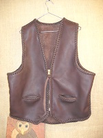  This brown leather vest has seams and edges that are completely braided. It has two slit hip pockets, a (YKK #10) brass zipper closure, and what I call a draft flap across the back/bottom of it. 