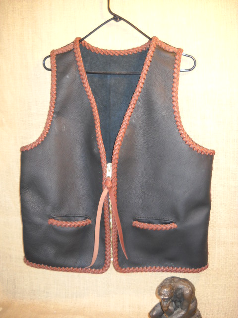  This braided (seams & edges) moccasin cowhide vest has no yoke/s, lapels. It does have two slit hip pockets and a large brass (YKK #10) zipper. 