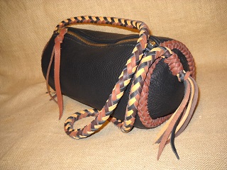  Here is one of the many bags on this page that I call my 'barrel bags' - it is about 12" long and has a 6" diameter. The bag has a large brass zipper across the top of it. It's dark Brown bag with a Rust colored seam braided on each end of it. The 8 strand round braided strap is of four colors. 