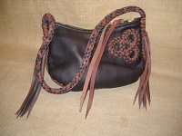  These two pictures show a dark Brown shoulder bag constructed with two-tone (dark Brown and Mahogany) leather braiding. It's 8 strand leather strap has long tassels on each end of it. It's closure is a large brass zipper that is attached with hand sewn 5 ply nylon thread ...and has a leather strap attached to its slide. 