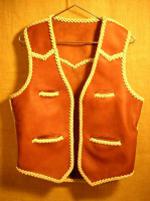  This moccasin cowhide leather vest was made in the USA. It features both front and back yokes that are all pointed. It has two slit breast pockets (credit card size) and two slit hip pockets. It also has the curved 3" draft flap extension at the back/bottom. Click on it for a larger view of it. 
